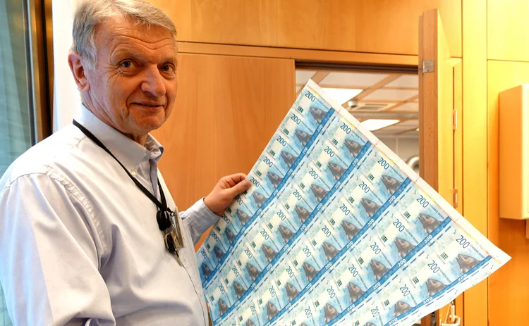 Trond Eklund holds up a sheet of 200 krone banknotes