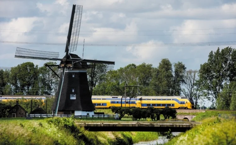 A train passes a windmill in Holland - photo Eneco