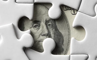 Dollar peeping out from beneath a jigsaw puzzle