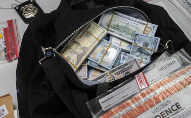 Duffel bag full of dollar banknotes with law enforcement badge and evidence bags