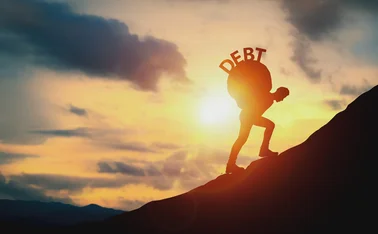 Man carrying the word ‘debt’ up a hill on his back