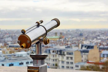Touristic telescope overlooking Montmartre hill with scenic city view in Paris, France