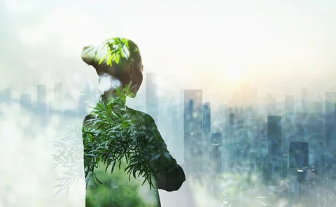 Silhouette of woman filled with greenery looking over a city scape