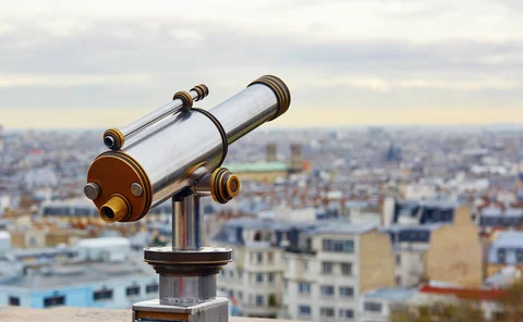 Touristic telescope overlooking Montmartre hill with scenic city view in Paris, France