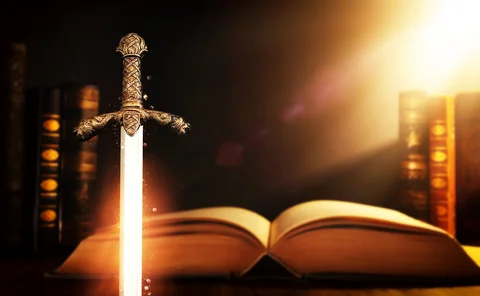 Magical sword shining and standing upright in front of old books in a library