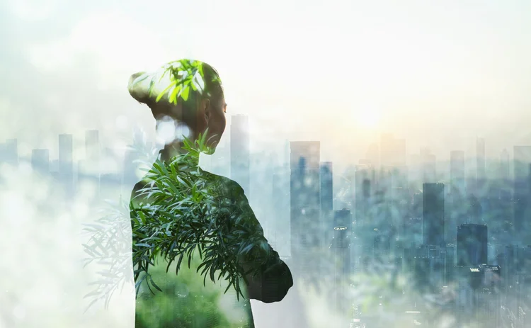Silhouette of woman filled with greenery looking over a city scape