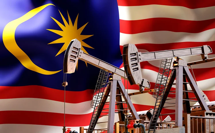 Two oil derricks in front of the Malaysian flag
