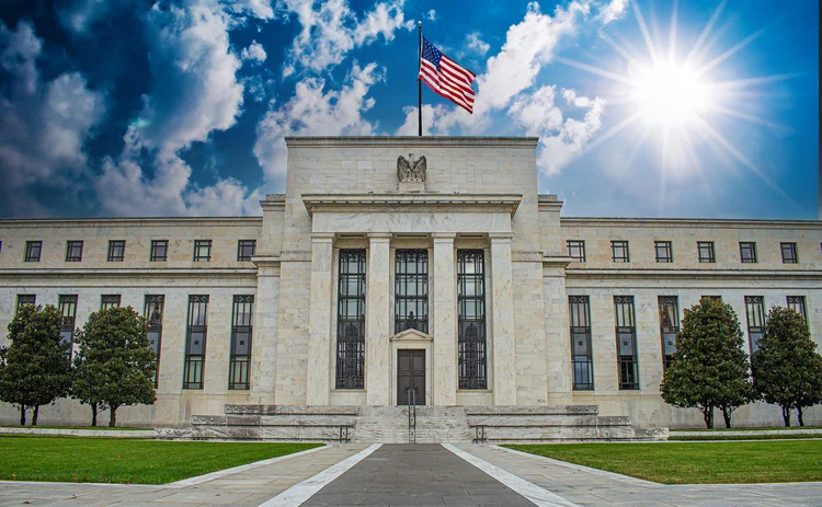 US Federal Reserve building with sky in background showing clouds to the left, bright sun to the right