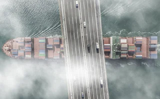 Container ship passes under a road bridge on a foggy day