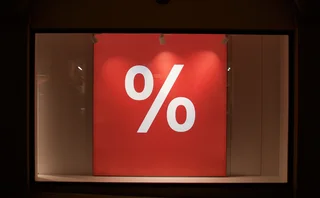 A large red percentage sign hanging in a shop window