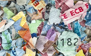 Close-up of shredded colorful banknotes, showing detailed security patterns, numbers, and anti-counterfeiting designs from various currencies