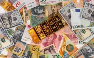 Gold ingots sit on top of banknotes from around the globe