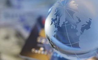 A close-up of a globe with a blurred out credit card, symbolising international payments