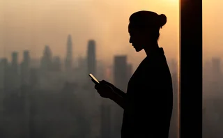 Silhouette of a female executive in front of a cityscape at sundown