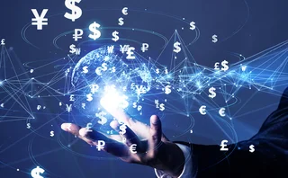 A businessperson’s hand hovers underneath a digital rendering of the earth, superimposed by international currency symbols connected by lines to show payment systems