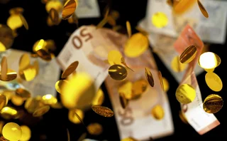 Euro bankotes and gold coins falling to the ground