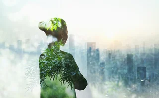 Silhouette of woman filled with greenery looking over a city scape